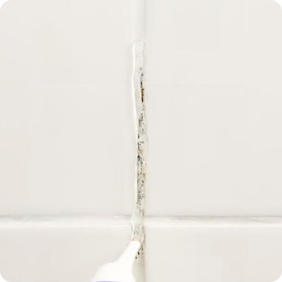 Application of NuroClean mold remover gel on bathroom tile grout with black mold stains.